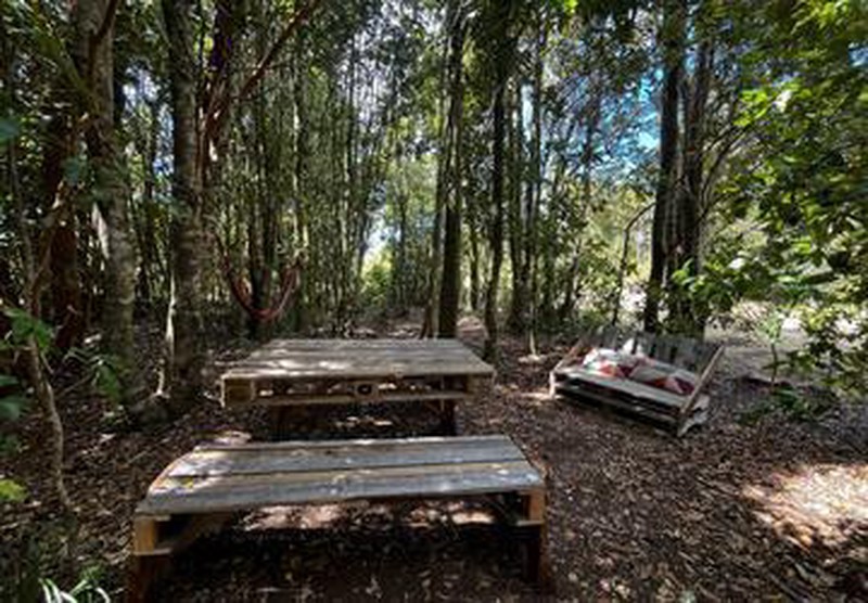Sitio de camping en Ko Glamping con mesa, bancas, sofá rústico y hamaca.
