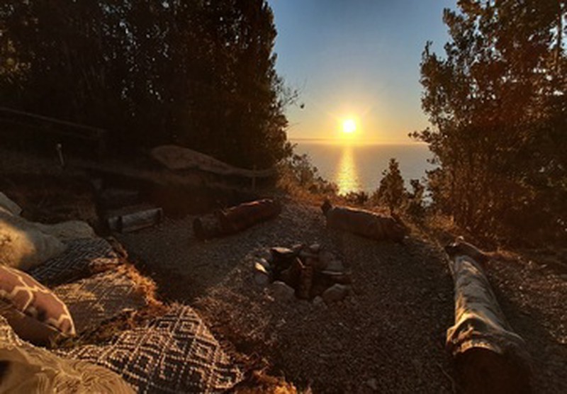 Fogón con asientos frente al océano en Ko Glamping, al atardecer.