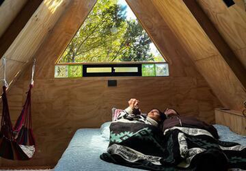 Pareja acostada en Refugio Pewma de Ko Glamping, mirando cielo a través del skylight.