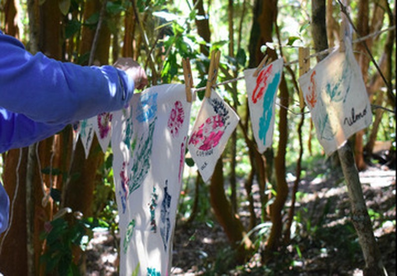 Manos colgando banderines estampados con hojas del bosque de Ko Glamping.